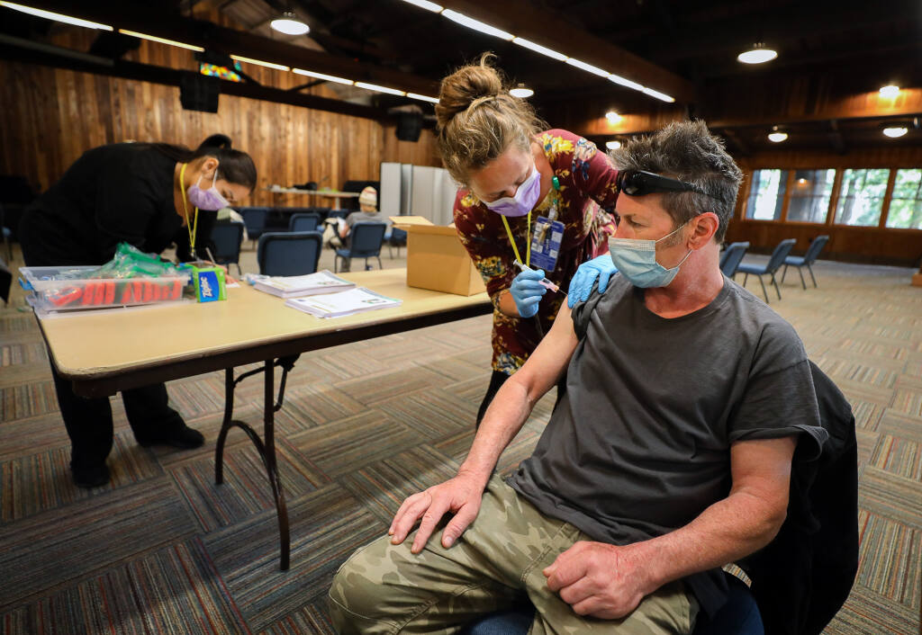 Santa Rosa Community Health registered nurse Natalie Hogan administers the Johnson & Johnson COVID-19 vaccine to Craig Petersen during a vaccine clinic for individuals in homeless shelters, at Alliance Redwoods near Occidental on Thursday, March 25, 2021.  (Christopher Chung / The Press Democrat)