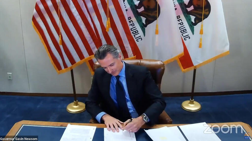 In this Sept. 30, 2020 file image made from video provided by the Office of the Governor, California Gov. Gavin Newsom signs into law a bill that establishes a task force to come up with recommendations on how to give reparations to Black Americans in Sacramento, Calif. (Office of the Governor via AP, File)
