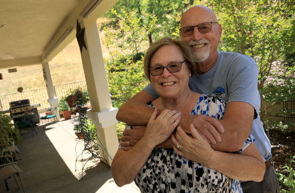 Lesley and Bruce Muller in the backyard of their Cloverdale home, Thursday, July 14, 2022, which backs up to seasonal grasses and forested hillsides.  The Muller's homeowners insurance was boosted several hundred dollars due to wildfire risk in the area.  (Kent Porter / The Press Democrat) 2022
