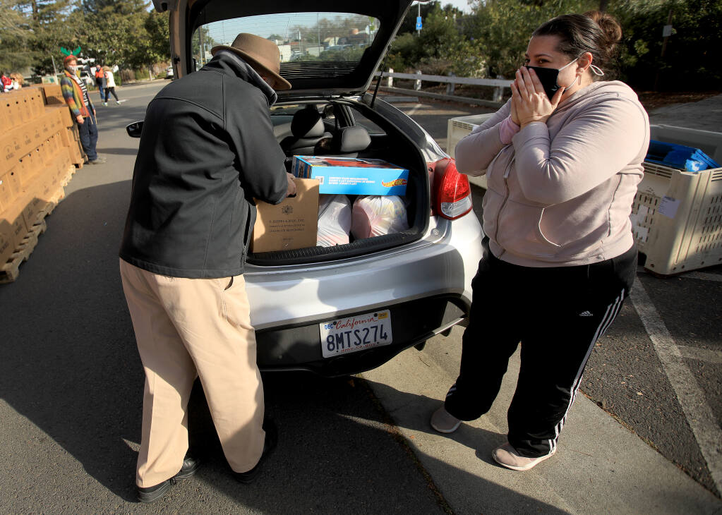 Sebastopol resident Elizabeth Fugere is overcome with emotion as Tim Passage of the Rotary Club of Sebastopol loads her car with groceries, Thursday, Dec. 24, 2020 in the parking lot of the Sebastopol Center for the Arts. (Kent Porter / The Press Democrat) 2020