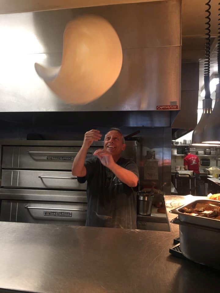 Tom Finch, owner of Filippi's Pizza Grotto in downtown Napa, flips a pizza in his restaurant's kitchen. (Photo courtesy Tom Finch)