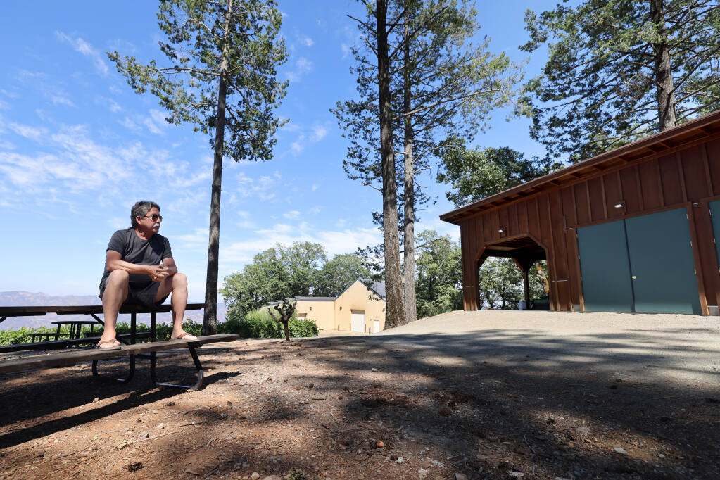 Sheldon Richards, owner of Paloma Vineyard, sits on a picnic table in Napa County whereas a portion of his winery building and garage is located in Sonoma County. Photo taken at Paloma Vineyard near St. Helena, Tuesday, Aug. 1, 2023. (Beth Schlanker / The Press Democrat)