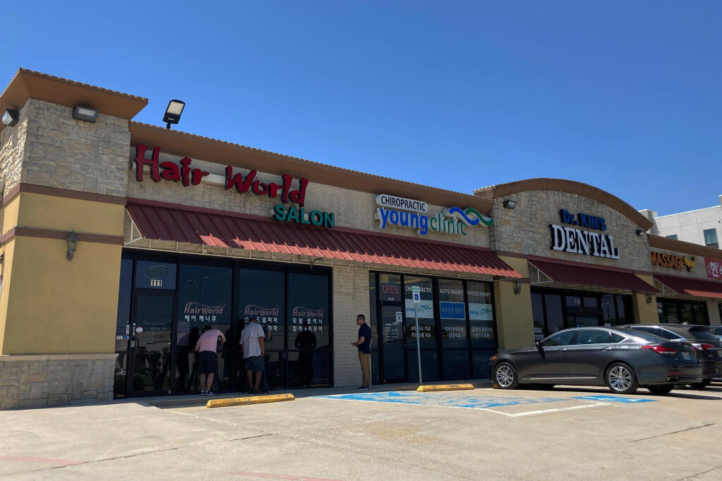 This photo shows the exterior of Hair World Salon in Dallas on Thursday, May 12, 2022. Police searched Thursday for a man who opened fire inside the hair salon in Dallas' Koreatown area, wounding three people. Authorities do not yet know why the man shot the three female victims Wednesday afternoon at Hair World Salon, which is in a shopping center with many businesses owned by Korean Americans. (AP Photo/Jamie Stengle)