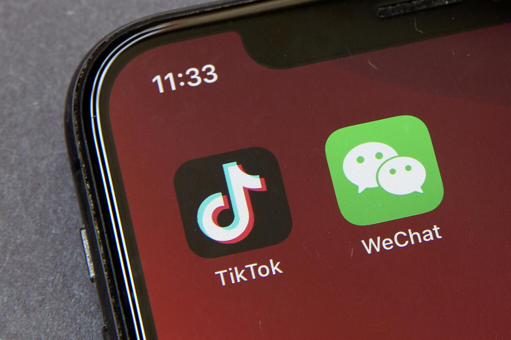 FILE - Icons for the smartphone apps TikTok and WeChat are seen on a smartphone screen in Beijing, in a Friday, Aug. 7, 2020 file photo.  Officials say the White House has dropped Trump-era executive orders that attempted to ban the popular apps TikTok and WeChat and will conduct its own review aimed at identifying national security risks with software applications tied to China. A new executive order directs the Commerce Department to undertake what officials describe as an “evidence-based” analysis of transactions involving apps that are manufactured or supplied or controlled by China. Officials are particularly concerned about apps that collect users’ personal data or have connections to Chinese military or intelligence activities. (AP Photo/Mark Schiefelbein, File)
