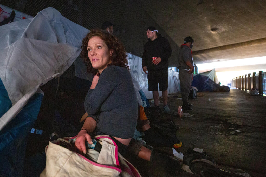 Jennifer McDonough, who has been homeless off and on for the past nine years, sits at her tent on Prince Memorial Greenway beneath Highway 101 in Santa Rosa on Tuesday, Dec. 8, 2020. (Alvin A.H. Jornada / The Press Democrat)