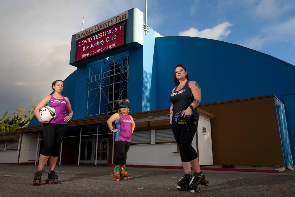 Sonoma County Roller Derby members, from left, Christina "Rainbow Spite" Pezzolo, Ashley "Crookskates" Taylor and Erin "Lucille Balls" Stous pose for a portrait in front of Grace Pavilion, where roller derby bouts are held, at the Sonoma County Fairgrounds in Santa Rosa, California, on Friday, November 6, 2020. (Alvin A.H. Jornada / The Press Democrat)