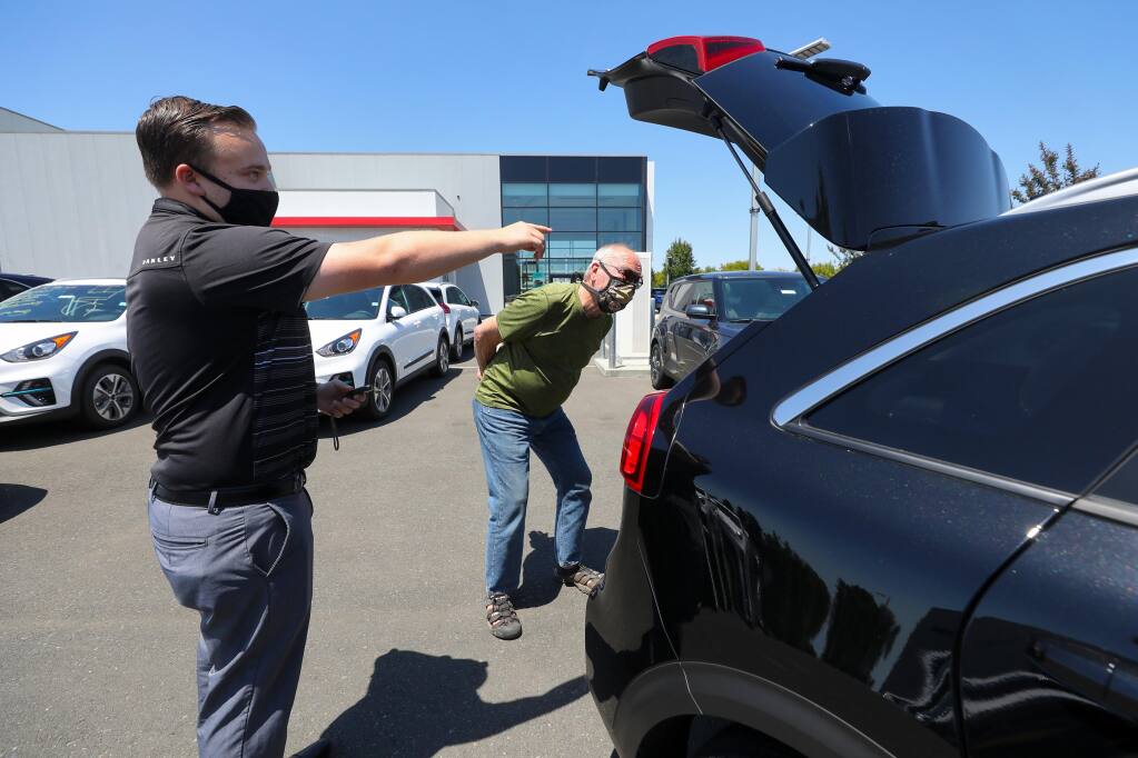 Salesperson Nathan Skeen, left, shows a Kia Niro to Tim Gilmore at the Jim Bone Kia dealership in Santa Rosa on Thursday, July 23, 2020.  (Christopher Chung/ The Press Democrat)