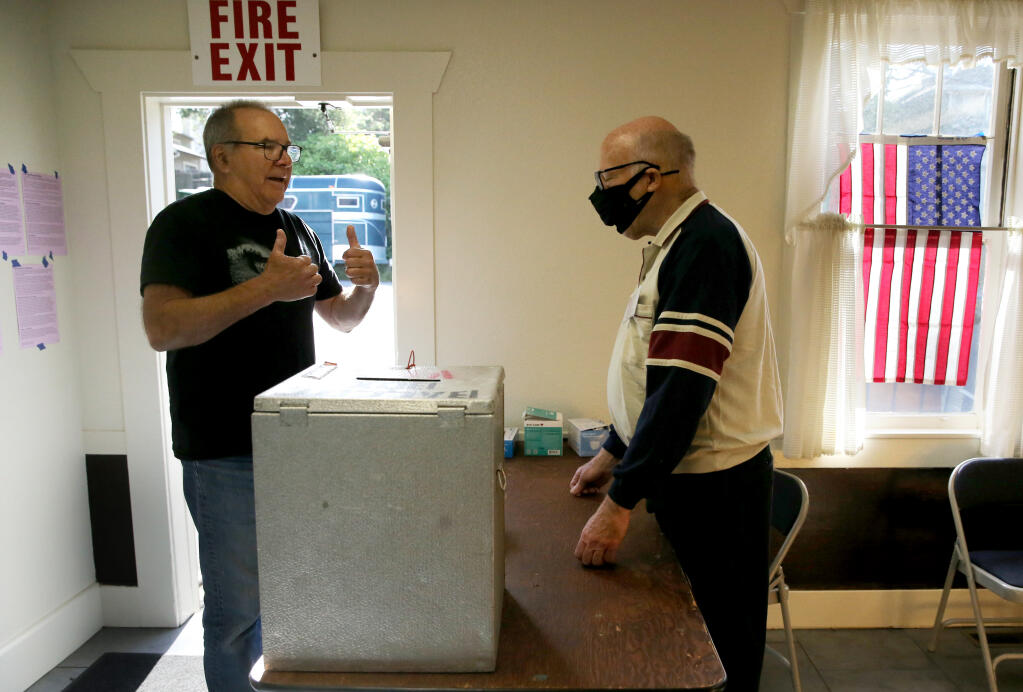 Chris Bergstedt, left, gives election worker Mark Strange a double thumbs up while dropping off his ballot at the Penngrove Social Fireman Clubhouse in Penngrove, Calif. on Tuesday, June 7, 2022. (Beth Schlanker/The Press Democrat)