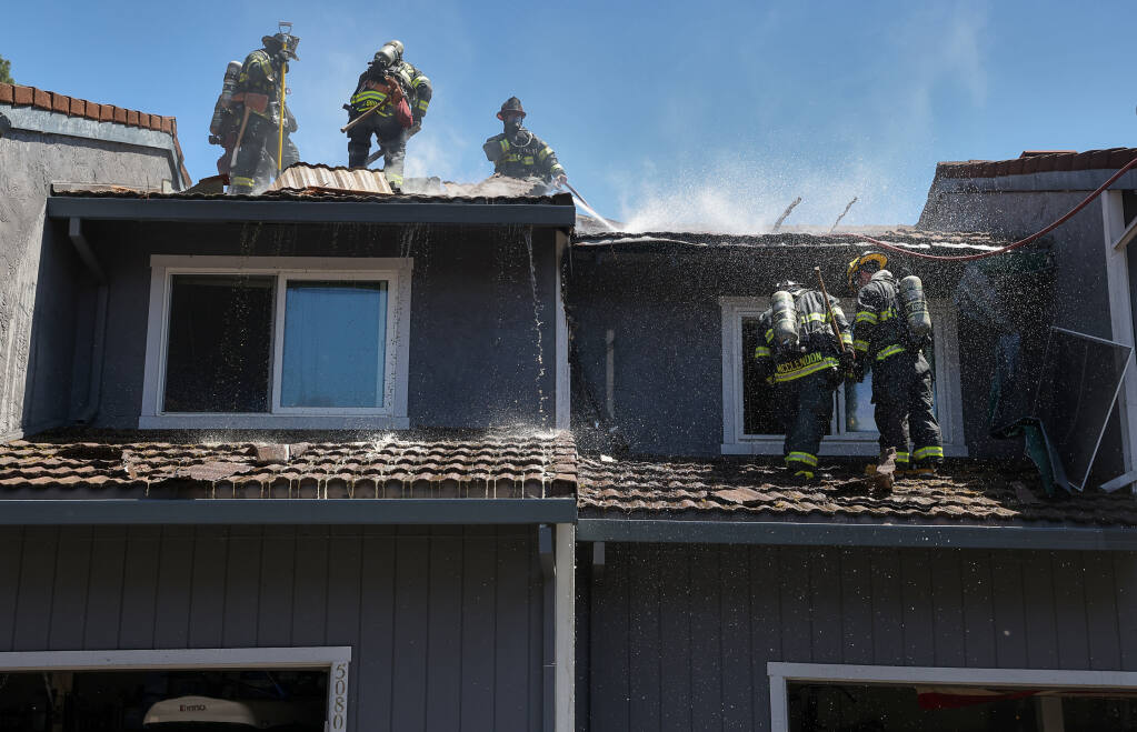 Santa Rosa Fire Department firefighters assist Rohnert Park Department of Public Safety firefighters on a structure fire at an apartment building on Country Club Drive in Rohnert Park on Monday, May 30, 2022.  (Christopher Chung/The Press Democrat)