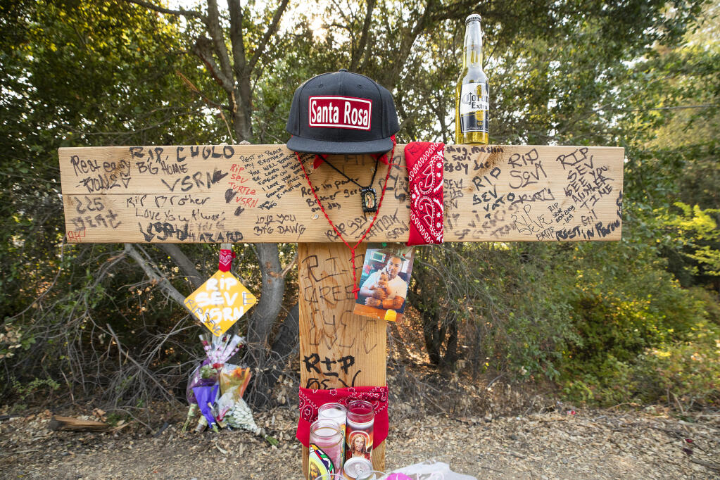 Dozens of friends have created a shrine for Severiano Alcantra, 32, of Windsor, who died in a crash off a sharp curve on Los Amigos Road just south of Limerick Lane on Monday, Aug. 16, 2021.  (John Burgess / The Press Democrat)