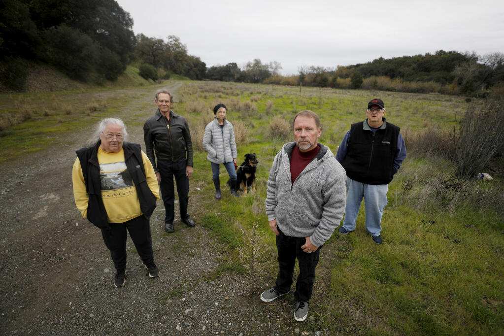 (From left) Lake Street East neighborhood residents Joy Gross, Richard St. Angelo, Denise Keller, Kevin Kostoff and Gary Gross stand at the site of the proposed Alexander Valley Family Apartments on Asti Road just north of Railroad Avenue in Cloverdale on Monday, Dec. 20, 2021. (Beth Schlanker/The Press Democrat)
