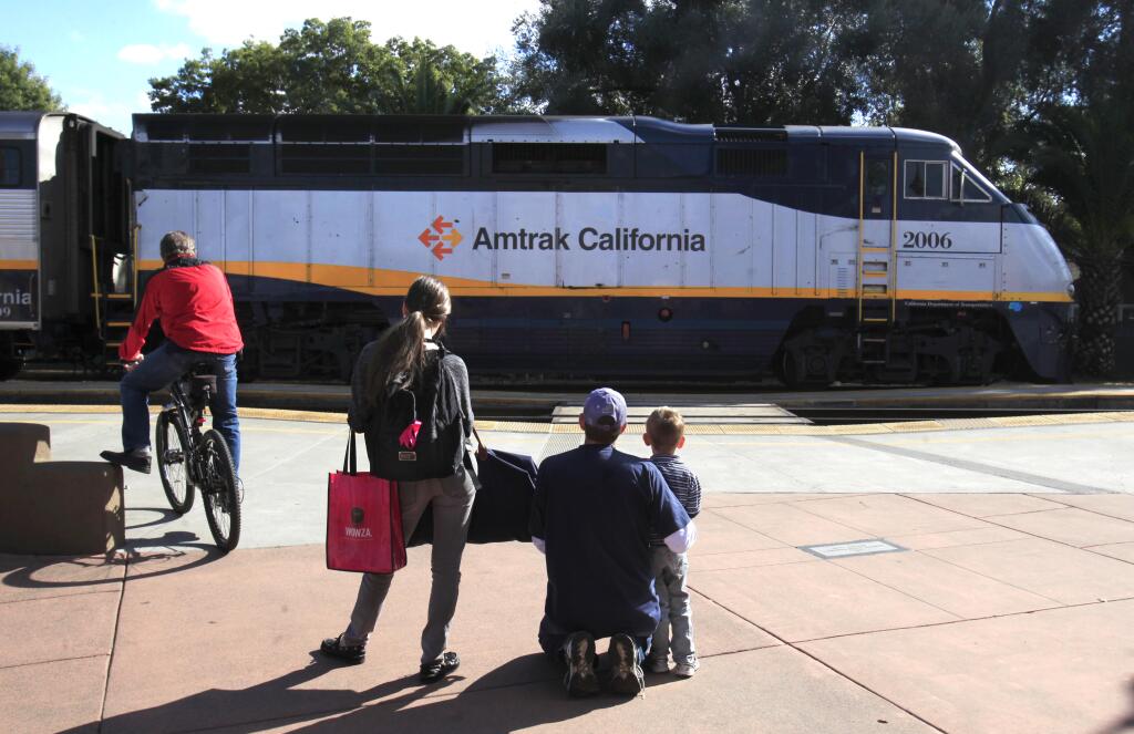 In this photo taken Friday, Nov. 4, 2011, David Roberts, kneeling center, his son Jeremey three-and-a-half, and niece Holly Bodsen, right, watch as Amtrak's Capitol Corridor passenger train departs Davis, Calif. (AP Photo/Rich Pedroncelli)