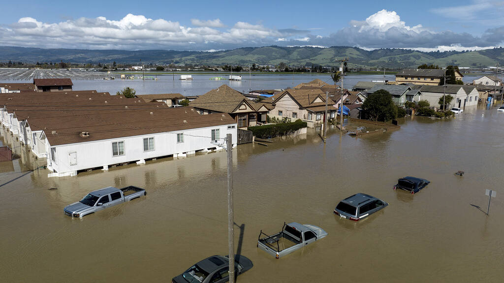 Floodwaters surround homes and vehicles in the Monterey County community of Pajaro. (NOAH BERGER / Associated Press)