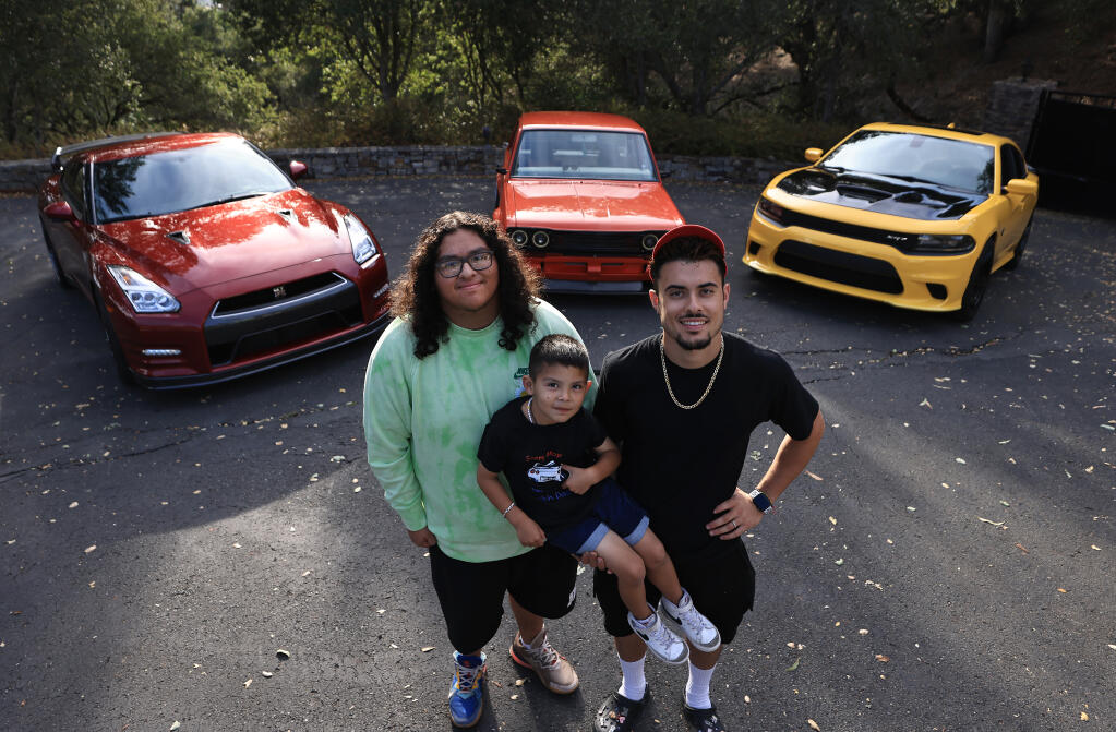 From left, Sergio Rendon Paz, brother Alex Rendon, 4, and Adrian Ochoa with from left, a 2015 Nissan GT-R, a 1970 Datsun 510. and a 2017 Dodge Hellcat, Tuesday, Sept. 19, 2022 near Santa Rosa. (The Press Democrat) 2022