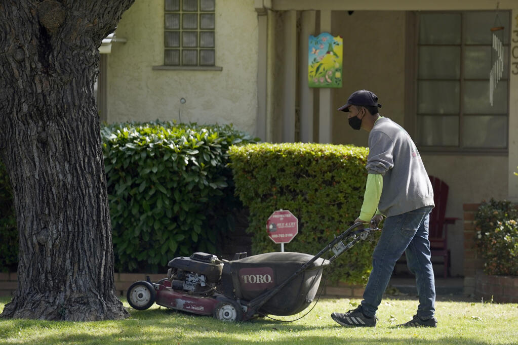FILE - A gardener mows a lawn at a home in Sacramento, Calif., on Oct. 13, 2021. (AP Photo/Rich Pedroncelli, File)