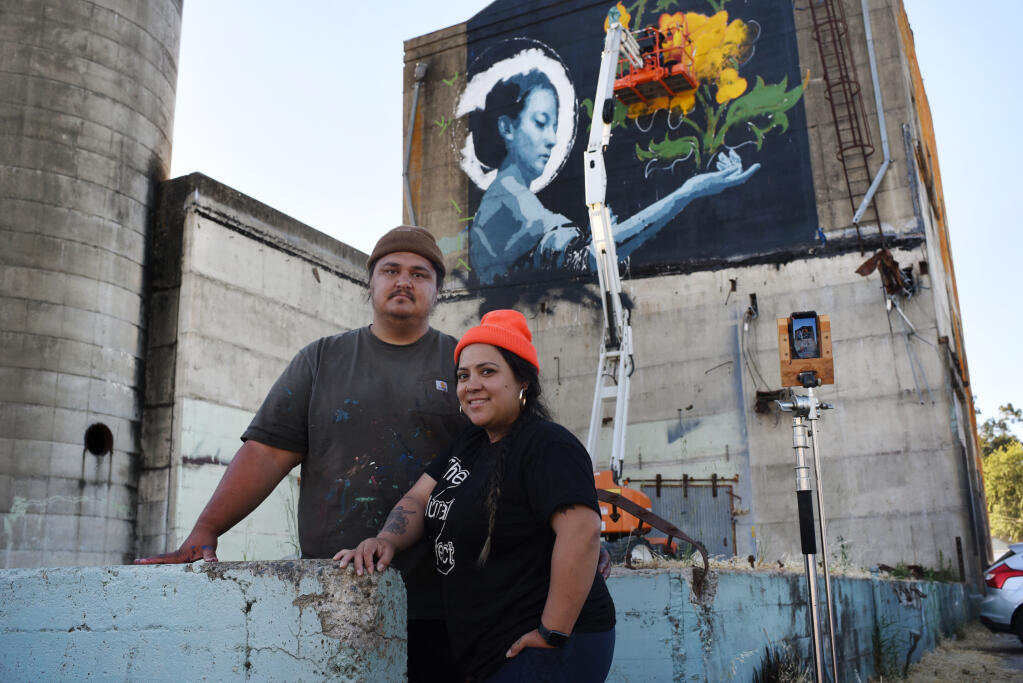 “I’d like to see Roseland eventually look like the Mission District,” said Joshua Lawyer, left, with MJ Lindo-Lawyer, co-founders of the Mural Festival beneath a mural in process by artist John Wentz on a vacant building on Sebastopol Road in the Roseland neighborhood of Santa Rosa, Calif. on Monday, June 27, 2022. (Erik Castro / For The Press Democrat)