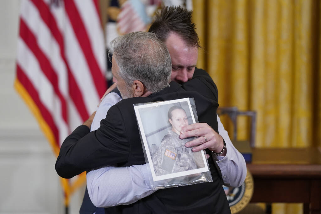 Activist and entertainer Jon Stewart hugs Sri Benson, husband of Katie Benson who served in Kuwait and died of mesothelioma, as they arrive to attend an event where President Joe Biden will sign the "PACT Act of 2022" in the East Room of the White House, Wednesday, Aug. 10, 2022, in Washington. (AP Photo/Evan Vucci)