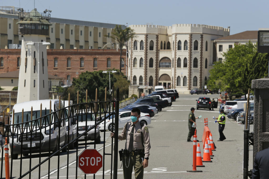 FILE - This July 9, 2020, file photo shows a correctional officer closing the main gate at San Quentin State Prison in San Quentin, Calif.  (AP Photo/Eric Risberg, File)