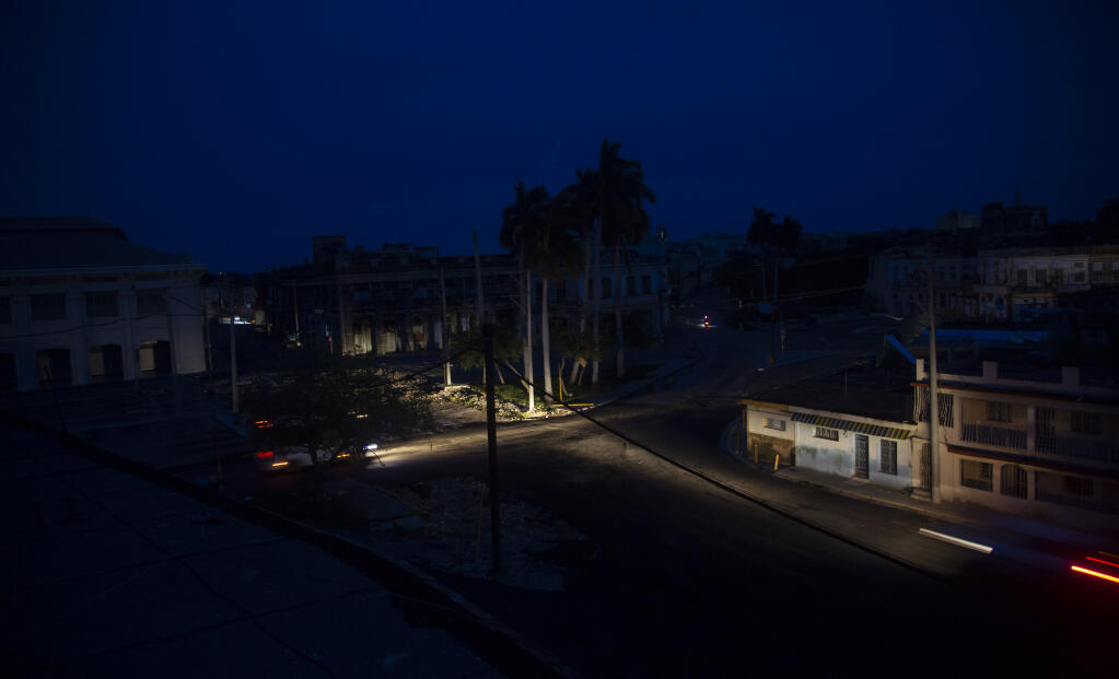 Vehicle headlights illuminate the street during a blackout triggered by Hurricane Ian in Havana, Cuba, early morning Wednesday, Sept. 28, 2022. Hurricane Ian knocked out electricity to the entire island when it hit the island’s western tip as a major storm. (AP Photo/Ismael Francisco)