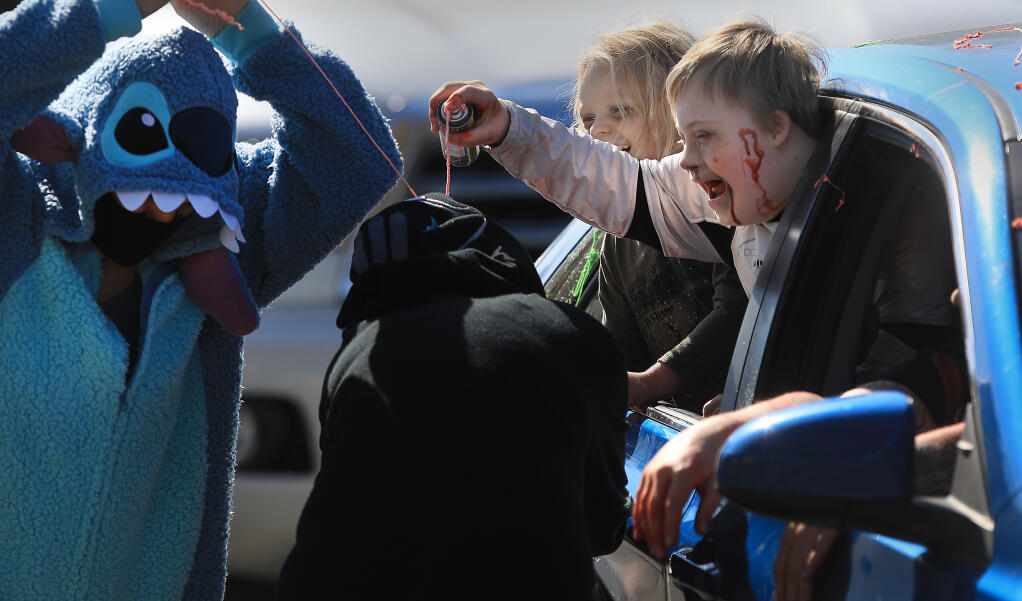 Memphis Borelli, right, and his brother, Jeff, use silly string on teachers Krista Lua, middle, and Charlotte Harumi during a drive-by Halloween parade at Evergreen Elementary School, Friday, Oct. 30, 2020 in Rohnert Park.  (Kent Porter / The Press Democrat) 2020