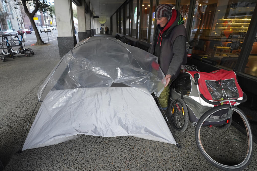 A homeless man sets up his tent in downtown Sacramento, where city officials and business owners are at odds over a ballot measure requiring more shelter space. (RICH PEDRONCELLI / Associated Press)