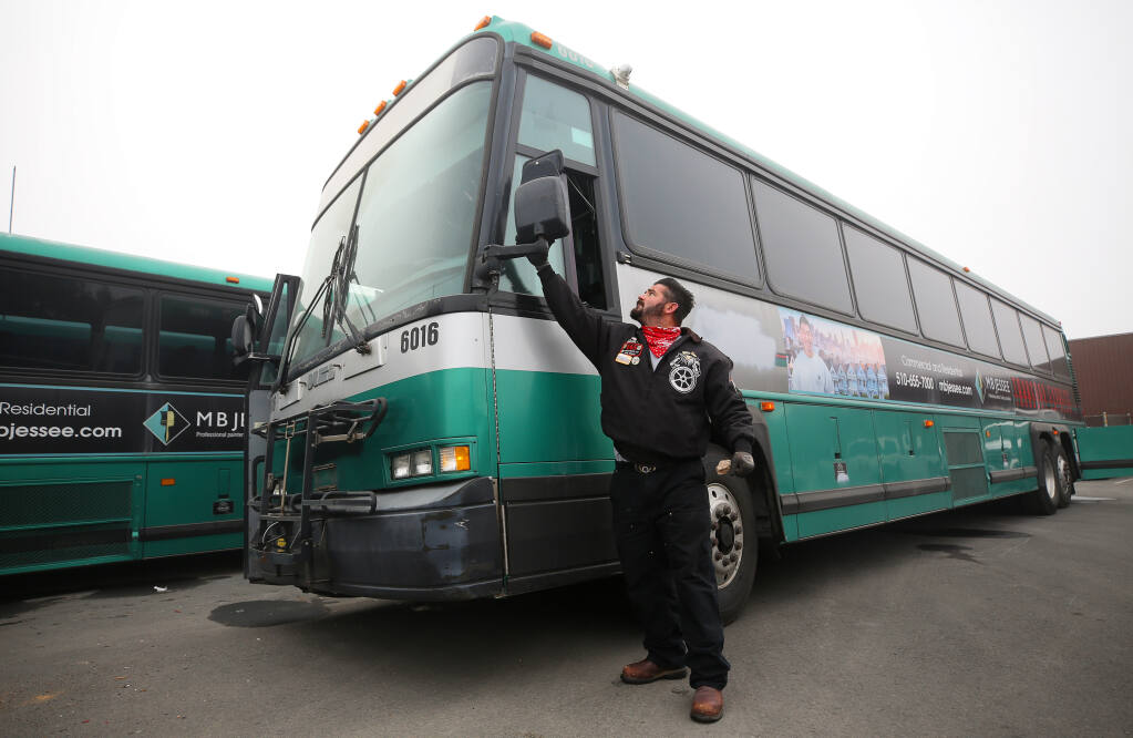 Robert Conklin wipes off a side mirror of one of the three buses being driven across the country by local Teamsters in Santa Rosa on Thursday, Sept. 17, 2020. The three buses and an ambulance are being delivered to Haiti through Those Angels, Inc. (Christopher Chung / The Press Democrat)