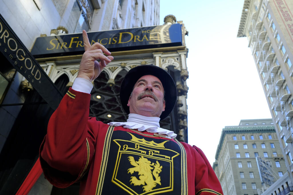 Beefeater doorman Tom Sweeney points up Powell Street while standing outside the Sir Francis Drake Hotel in San Francisco. He retired in early 2020, after 43 years. (AP Photo/Eric Risberg)