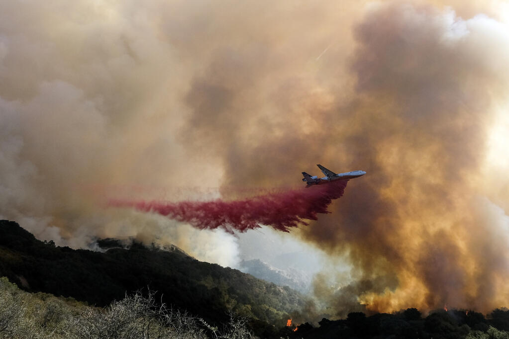 FILE - In this Oct. 13, 2021, file photo, an air tanker drops retardant on a wildfire in Goleta, Calif. (AP Photo/Ringo H.W. Chiu, File)