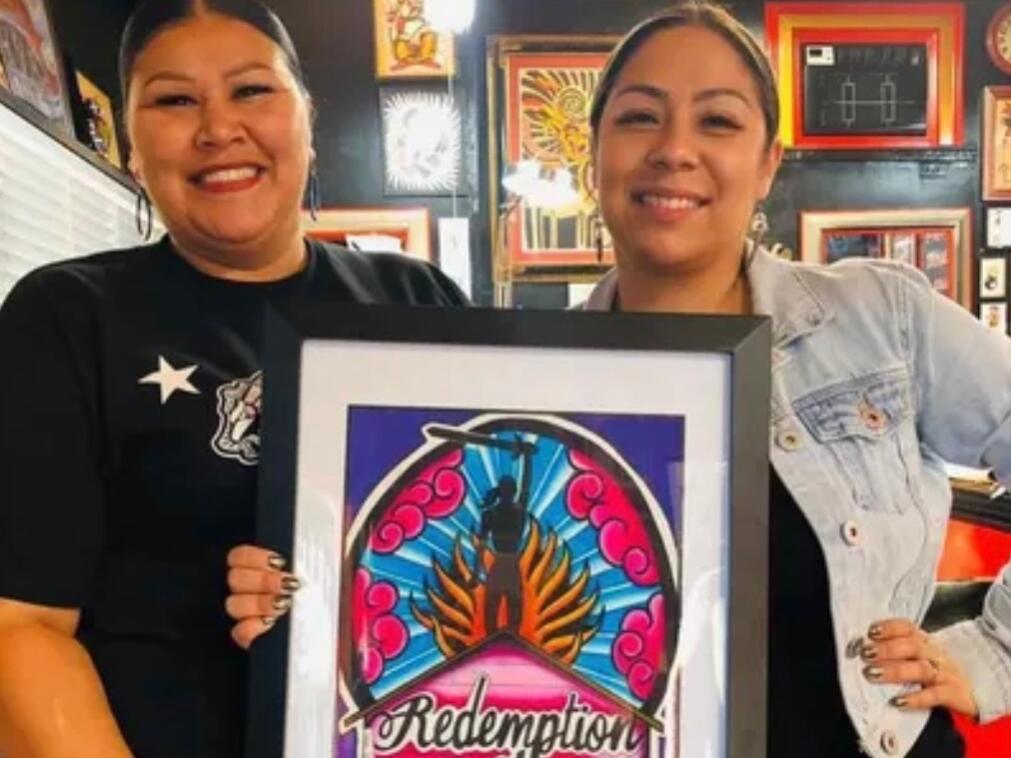 Lisa Diaz-McQuaid and Elizabeth Quiroz pose with a picture of the logo for Redemption House, the nonprofit group they co-founded to help victims of human trafficking. (Redemption House)