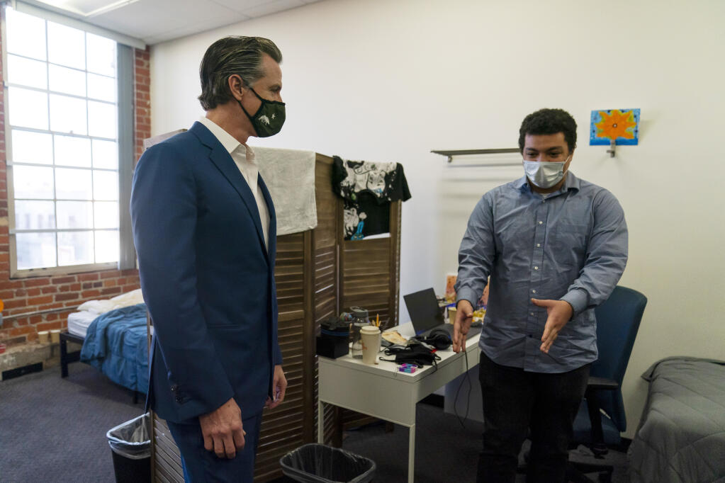 FILE - California Gov. Gavin Newsom, left, listens to Zachary Wright, a 25-year-old patient at Project 180, while visiting the facility in Los Angeles on March 10, 2022. Gov. Newsom's proposal to connect more homeless people to mental health services is making its way through the Legislature despite deep concerns by legislators that there isn't enough staffing or housing to make the program work while forcing people into treatment against their will. (AP Photo/Jae C. Hong, File)