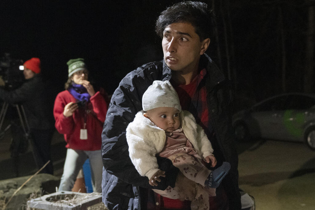 Asylum seeker Mahamed Yusef Niazi, from Afghanistan, carries his seven-month-old daughter Sahaba, across the border at Roxham Road from New York into Canada on Friday, March 24, 2023 in Champlain, N.Y. The irregular border crossing will be closed permanently tonight at midnight. (Ryan Remiorz/The Canadian Press via AP)