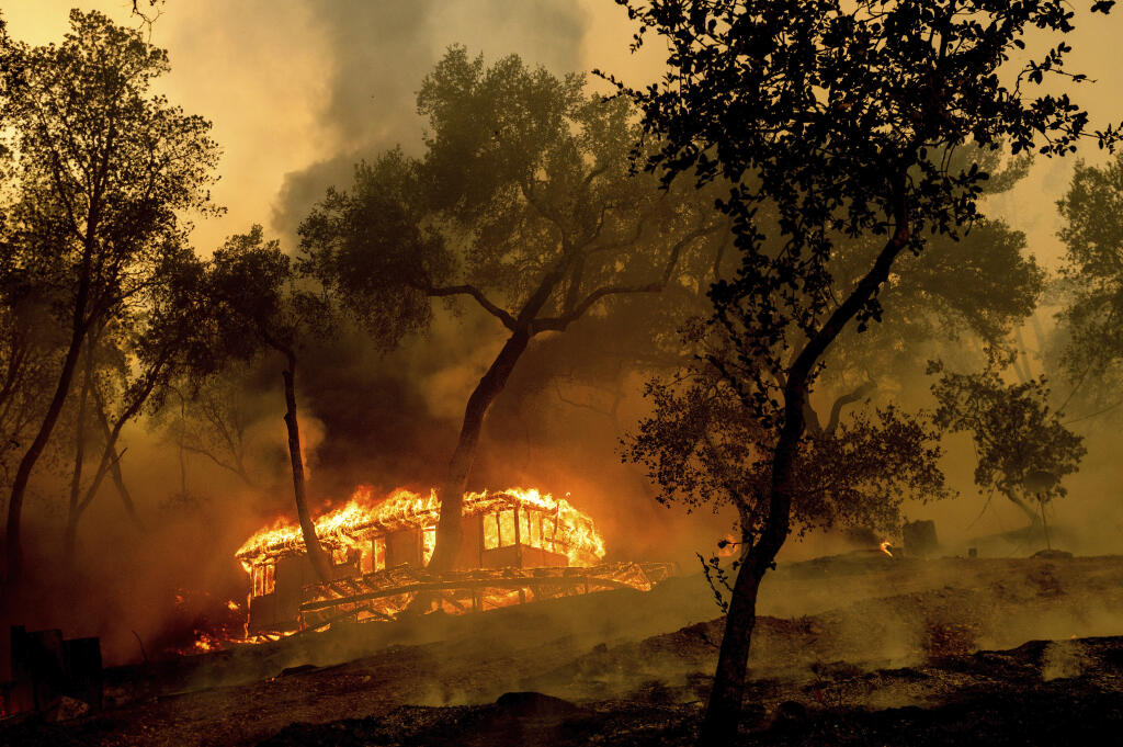 Flames consume a cabin at the Nichelini winery in unincorporated Napa County as the Hennessey Fire burns on Tuesday, Aug. 18, 2020.  A winery family member said they had spent 10 hours Monday rebounding the cabin's foundation. Fire crews across the region scrambled to contain dozens of blazes sparked by lightning strikes as a statewide heat wave continues. (AP Photo/Noah Berger)