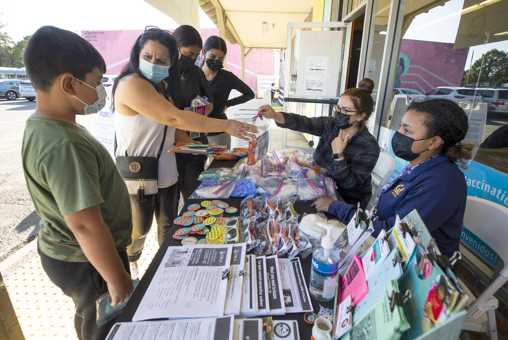 Sonoma County Outreach workers Ray Woodard and Yecenia Gonzalez hand out masks and hand sanitizer for the Mendoza family at a Spanish-language vaccine event at Roseland vaccination clinic on Friday, October 1, 2021. (Photo by John Burgess/The Press Democrat)
