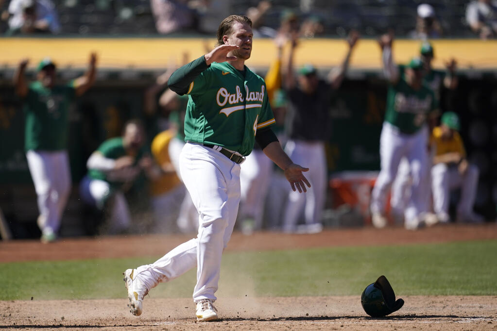 The Athletics’ David MacKinnon celebrates after scoring on a Skye Bolt sacrifice fly during the 10th inning against the Miami Marlins Wednesday in Oakland. (Jeff Chiu / ASSOCIATED PRESS)