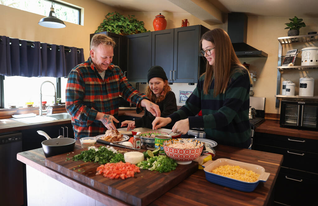 Sheldon Rosenberg, left, prepares dinner with his daughters Alexis, 11, and Ava, 15, in Sebastopol on Friday, April 15, 2022.  Rosenberg is traveling to Poland on Sunday to drive supplies and transport families with autistic children who have special needs for twelve days. (Christopher Chung/ The Press Democrat)