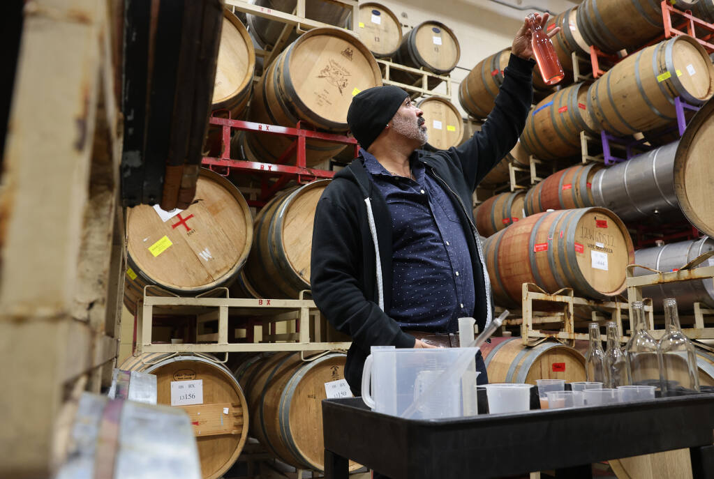 Chris Christensen, owner and winemaker at Bodkin Wines, holds a freshly blended bottle of rosé wine up to the light in Sebastopol on Monday, February 7, 2022.  (Christopher Chung/ The Press Democrat)