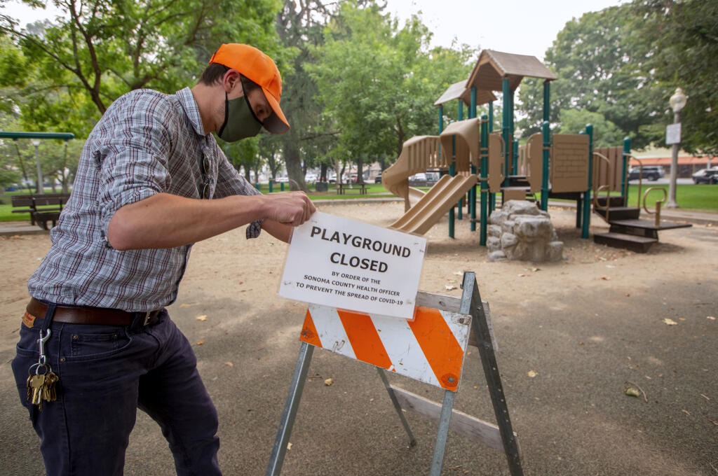 Chris Pegg removes the ‘Playground Closed’ sign from the Plaza playground on Oct. 1, 2020. (Photo by Robbi Pengelly/Index-Tribune)