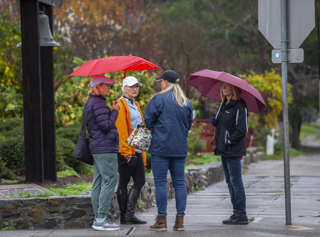 Sporadic rain showers fell in Sonoma on Monday morning, Dec. 13, 2021, bringing out the umbrellas for this group in front of the Mission on East Spain Street. (Photoby Robbi Pengelly/Index-Tribune)