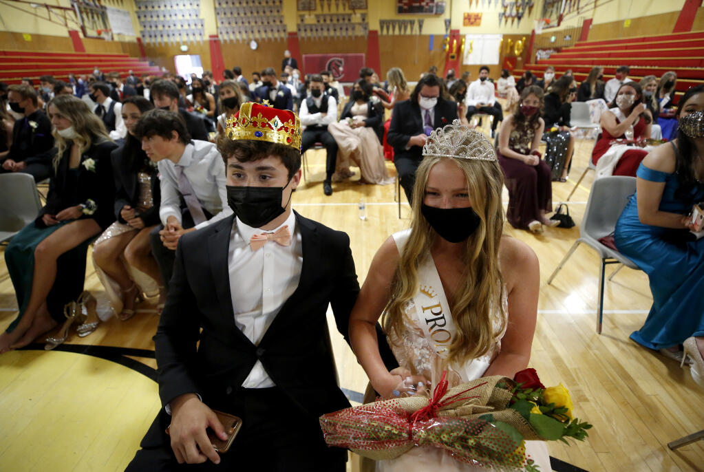 Seniors Bailey Ayre and Ally Ostheimer who were named prom king and queen, watch a senior tribute photo slideshow during prom at Cardinal Newman High School in Santa Rosa, Calif., on Friday, April 23, 2021. (Beth Schlanker/ The Press Democrat)