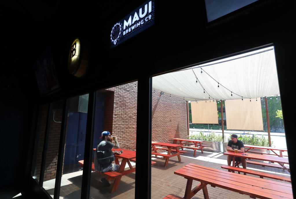 David Finkelstein, left, and Brooks Emerson drink beer in the outdoor patio of Flagship Taproom in Santa Rosa on Monday, July 13, 2020.  The taproom closed its indoor seating area Monday due to reinstated coronavirus restrictions.  (Christopher Chung/ The Press Democrat)