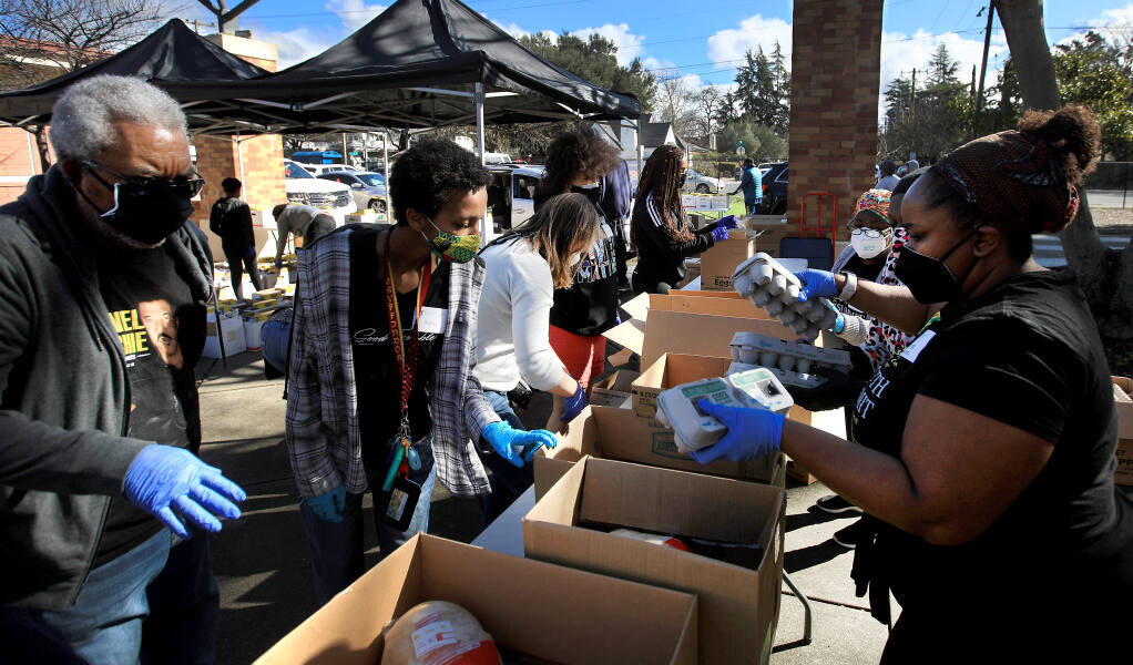 Volunteers with the Sonoma County Black Forum box up groceries during a food giveaway in front of Santa Rosa High School's ArtQuest campus, Saturday, Feb. 20, 2021 in Santa Rosa. (Kent Porter / The Press Democrat) 2021