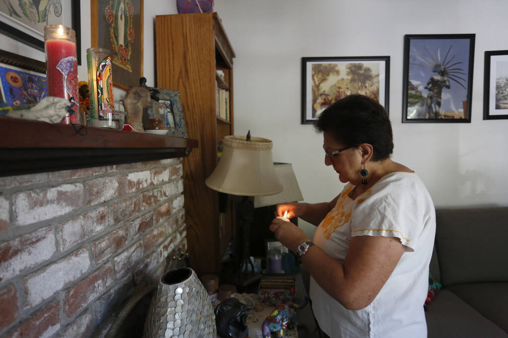 Laura Larqué lights a candle in her living room in Santa Rosa on Wednesday, Aug. 25, 2021. (Beth Schlanker/The Press Democrat)