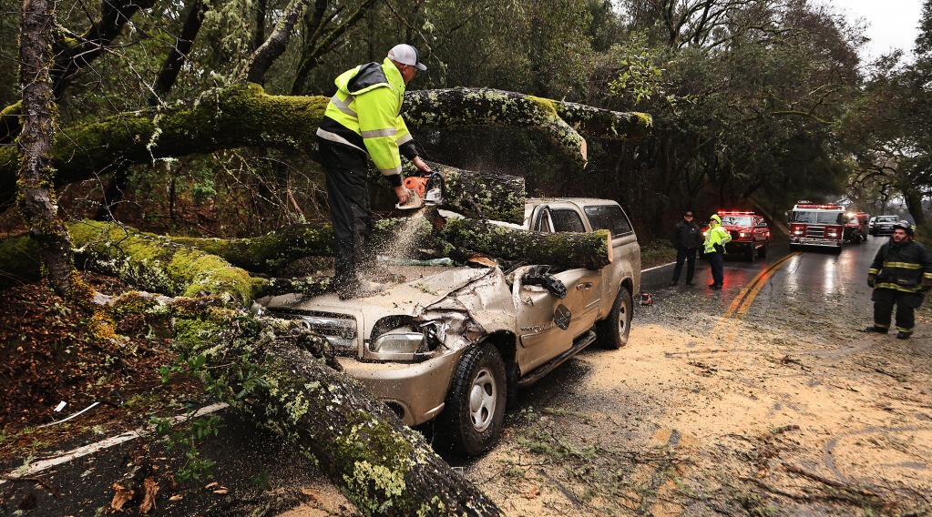 Hopland Volunteer Fire Department Chief Mitch Franklin cuts away a large oak tree that fell Saturday, Jan. 14, on a vehicle and injured the driver on Old River Road, north of Hopland in Mendocino County. (Kent Porter / The Press Democrat) 2023