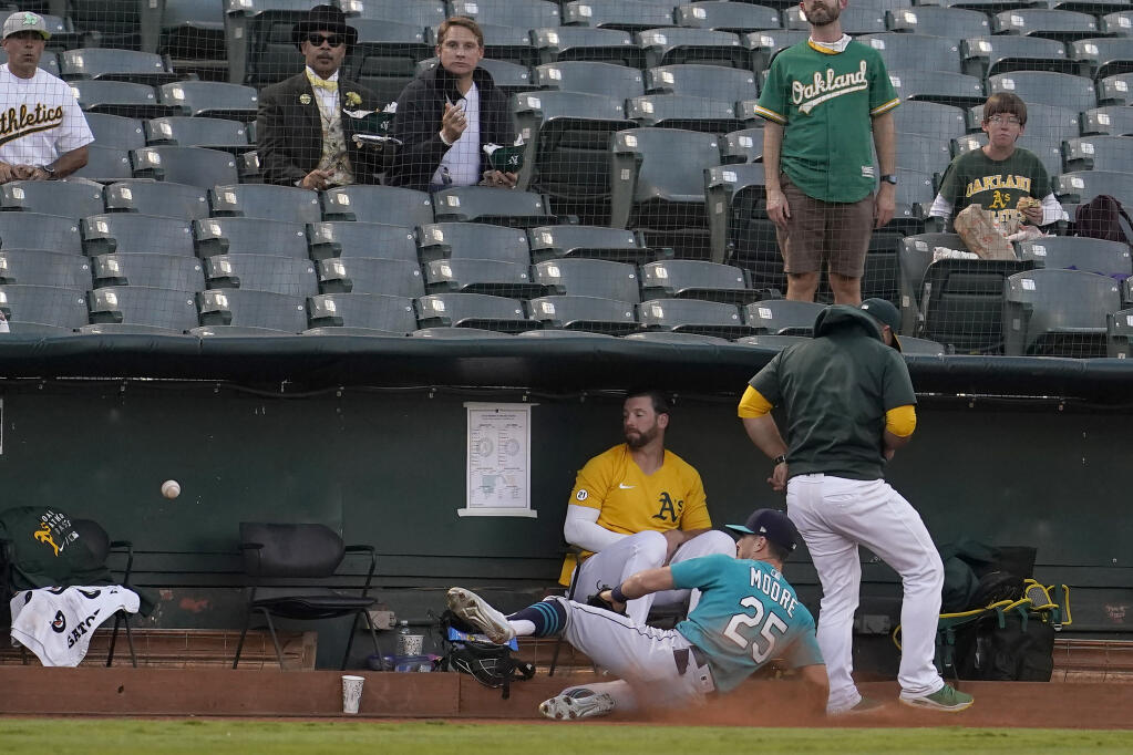Seattle Mariners left fielder Dylan Moore (25) cannot catch a foul ball hit by Oakland Athletics' Matt Olson as he slides into the Athletics bullpen during the first inning of a baseball game in Oakland, Calif., Monday, Sept. 20, 2021. (AP Photo/Jeff Chiu)
