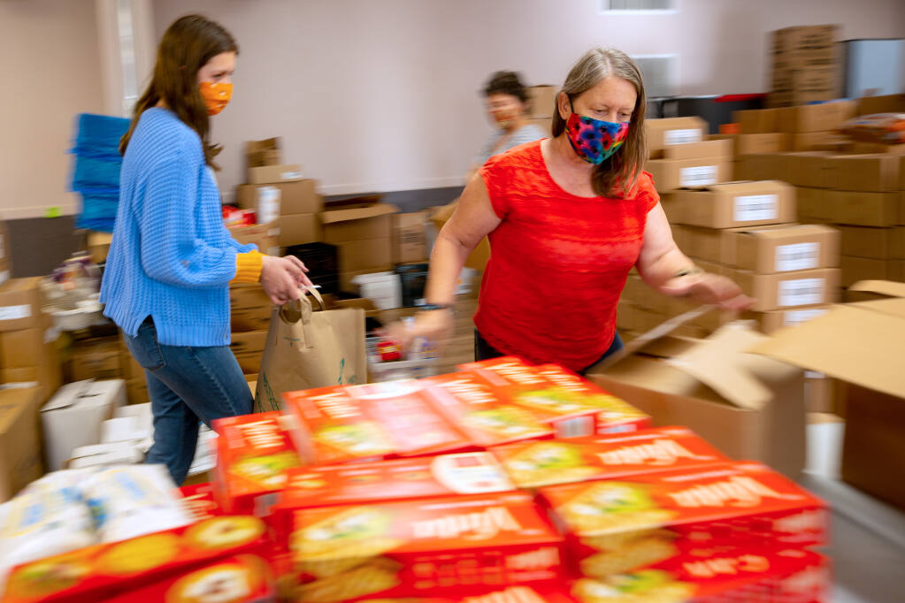 Lynne Gordon Moquete, executive director of Una Vida, and a corps of volunteers pack bags of food that are being given away to the local community, at Hillside Church in Petaluma, California, on Tuesday, Oct. 6, 2020. (Alvin A.H. Jornada / The Press Democrat)
