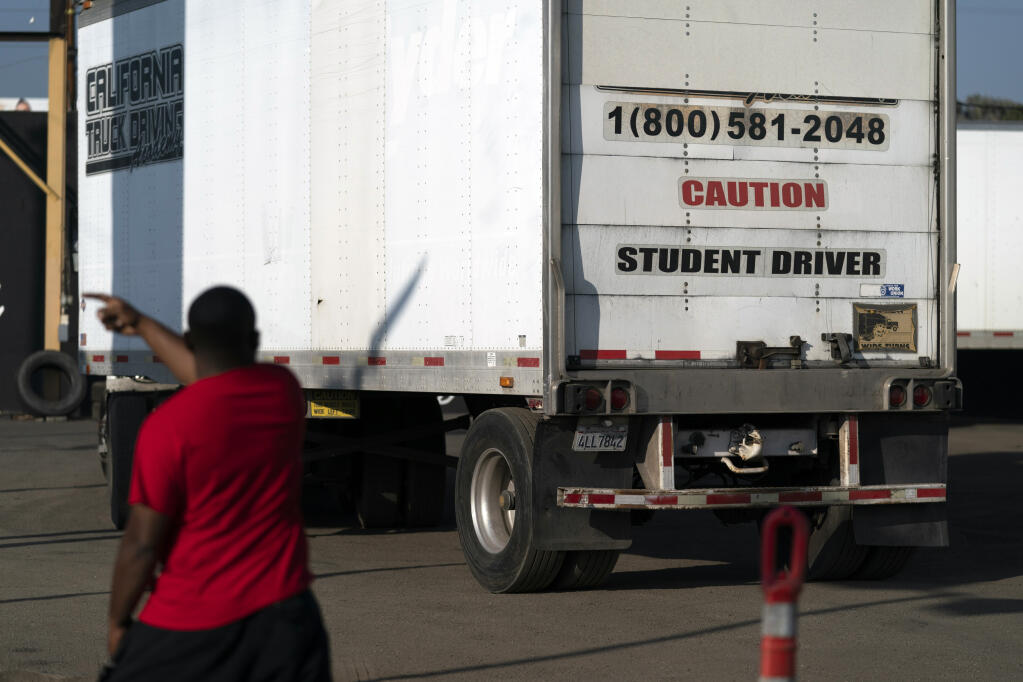 Student driver Stephen Gholar helps his classmate steer the wheel into the right direction as they practice driving in reverse at California Truck Driving Academy in Inglewood, Calif., Wednesday, Nov. 17, 2021. (AP Photo/Jae C. Hong)