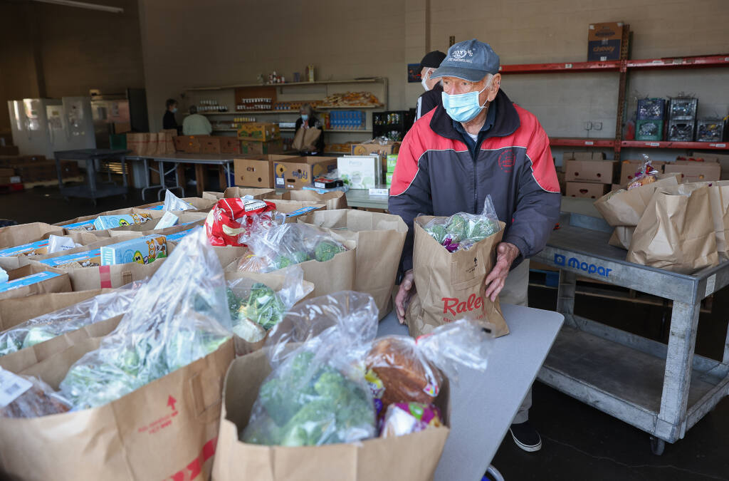Volunteer Stanley Hellman prepares bags of food for people in need at F.I.S.H. of Santa Rosa, Thursday, April 28, 2022. (Christopher Chung/ The Press Democrat file)