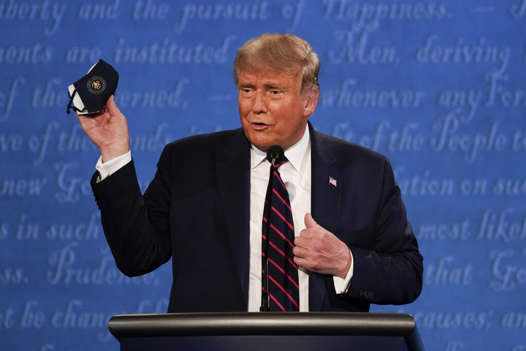 President Donald Trump holds up his face mask during the first presidential debate Tuesday, Sept. 29, 2020, at Case Western University and Cleveland Clinic, in Cleveland, Ohio. (AP Photo/Julio Cortez)