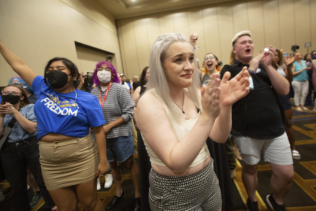 Allie Ugley, middle, an Allen County resident, holds back tears after hearing the news that the "No" votes won on a proposed amendment to the Kansas Constitution from the Kansans for Constitutional Freedom election watch party at the Overland Park Convention Center in Overland Park, Kan., Tuesday, Aug. 2, 2022. (Evert Nelson/The Topeka Capital-Journal via AP)