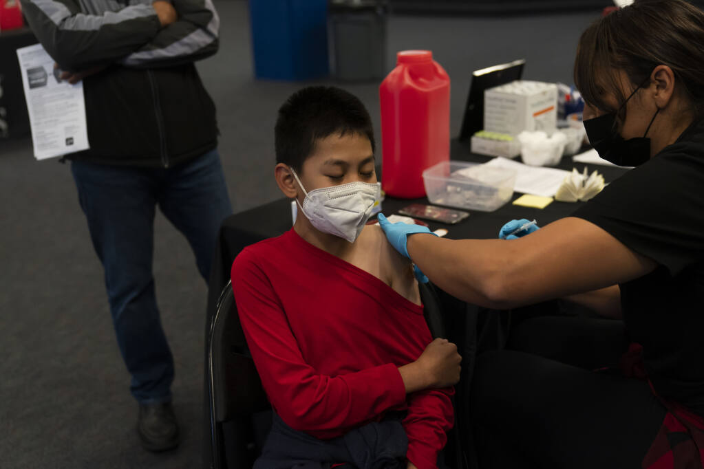 FILE - Johnny Thai, 11, receives the Pfizer COVID-19 vaccine at a pediatric vaccine clinic for children ages 5 to 11 set up at Willard Intermediate School in Santa Ana, Calif., Nov. 9, 2021. On Friday, Feb. 3, 2023, the California Department of Public Health said it was no longer exploring emergency rules to add the COVID-19 vaccine to the list of required school vaccinations. (AP Photo/Jae C. Hong,File)